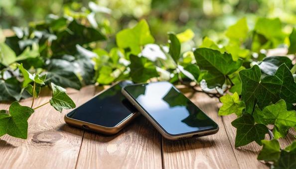連絡交換のイメージ 机の上の携帯電話二台 連絡交換のイメージ 机の上の携帯電話二台の写真