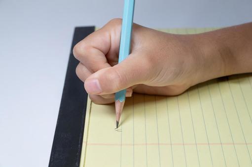 黄色いレポートパッドに鉛筆で書く手元 鉛筆,書く,手の写真素材