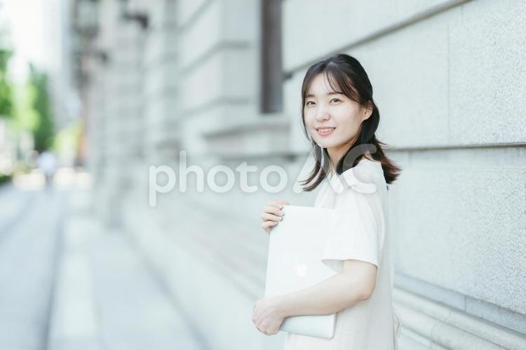 ノートパソコンを持って振り返る女性 屋外,女性,日本人の写真素材
