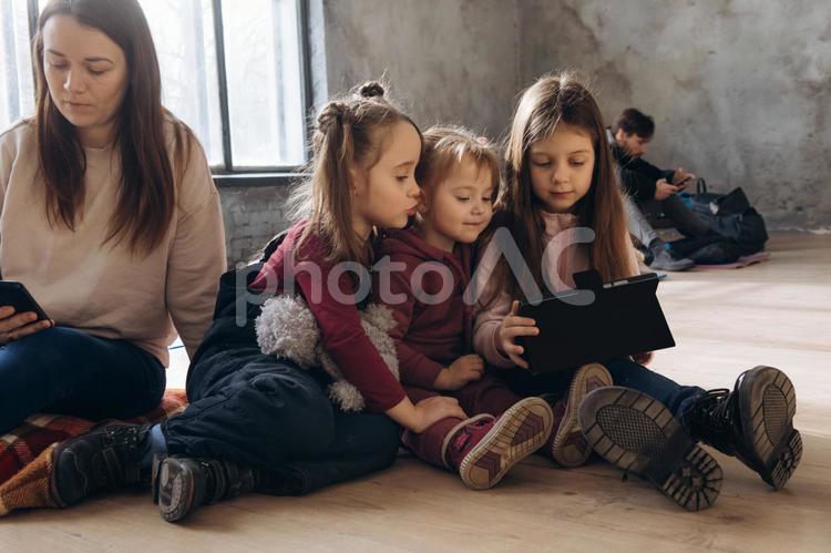 タブレットを見る女の子たちと後ろに男性など 女性,女の子,人物の写真素材