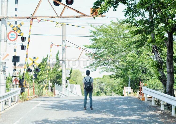 踏切の前に佇む男性 緑,男性,踏切の写真素材