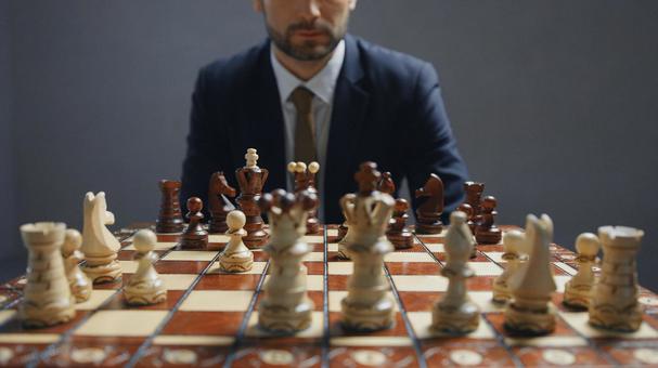 チェスをしているスーツ姿の男性(グレー背景) チェスをしているスーツ姿の男性(グレー背景)の写真