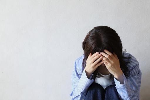 下を向いて落ち込む女性 下を向いて落ち込む女性の写真