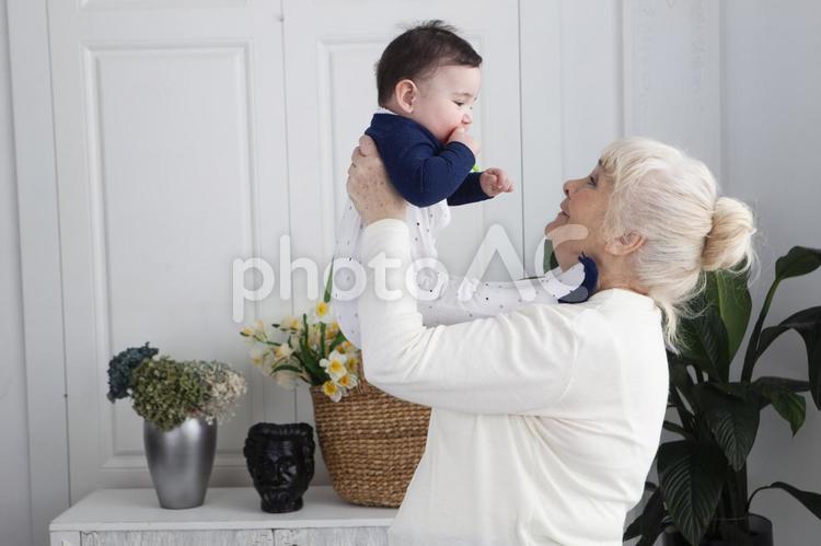孫を抱き上げる白髪のおばあさん 祖母,孫,抱っこの写真素材