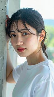 白いTシャツの女性が壁際でポーズをとる 白いTシャツの女性が壁際でポーズをとるの写真