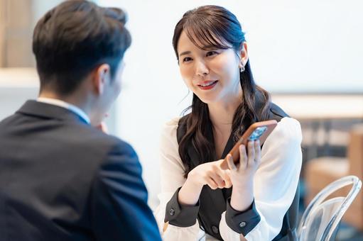 携帯を見ながら話す女性 笑顔,会話,打ち合わせの写真素材