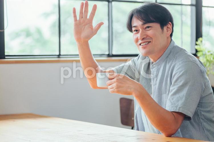 カフェでドリンクを飲む男性（手を振る） カフェ,コーヒー,待ち合わせの写真素材