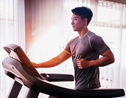 ランニングマシンでトレーニングする男性 ランニングマシンでトレーニングする男性の写真