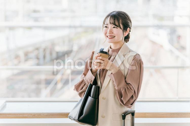 駅でコーヒーを飲みながら人を待つ女性 コーヒー,女性,デートの写真素材