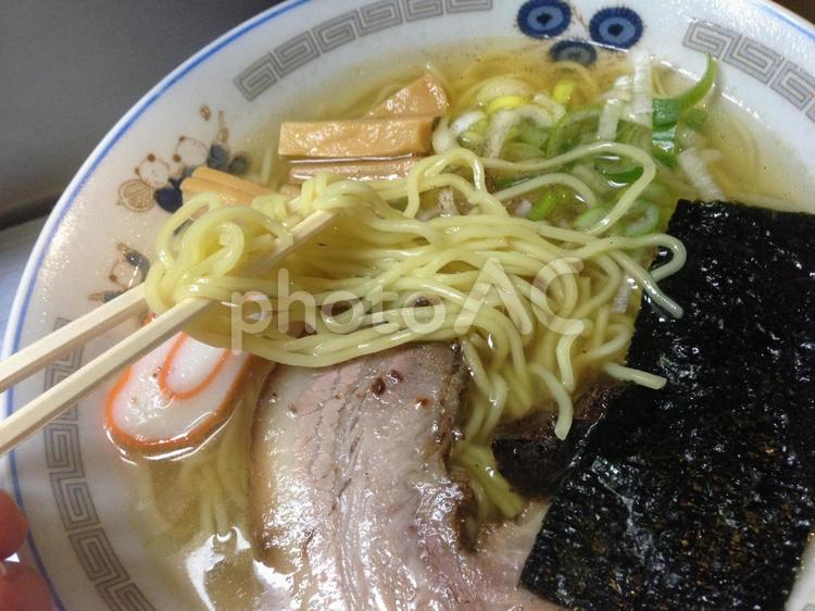 透明スープの屋台の塩ラーメンの麺リフト 麺リフト,左利き,割り箸の写真素材