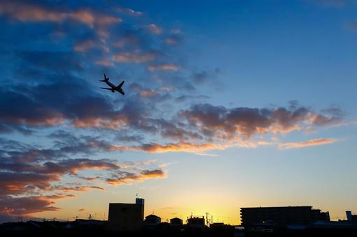街と夕焼けを飛ぶ飛行機 飛行機,シルエット,夕焼けの写真素材