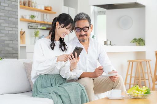 リビングでスマホを見るミドルの夫婦 リビングでスマホを見るミドルの夫婦 夫婦,家族,ミドルの写真素材