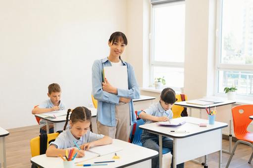 カメラ目線の先生と勉強する生徒 女性,女の子,男の子の写真素材