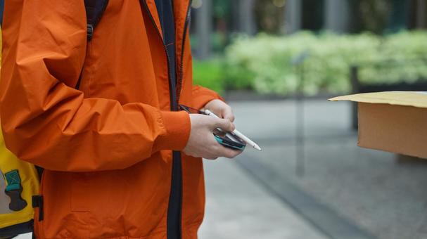 配達物を渡したあとに受取サインの端末を手に持っている配達員 配達,フードデリバリー,デリバリーの写真素材