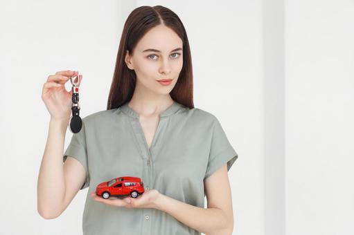 ストラップと赤い車の模型を持った女性 保険業,事務職,接客業の写真素材