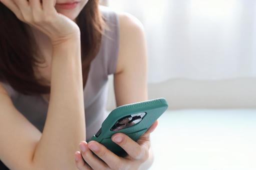 A woman looking at her smartphone and worrying, JPG