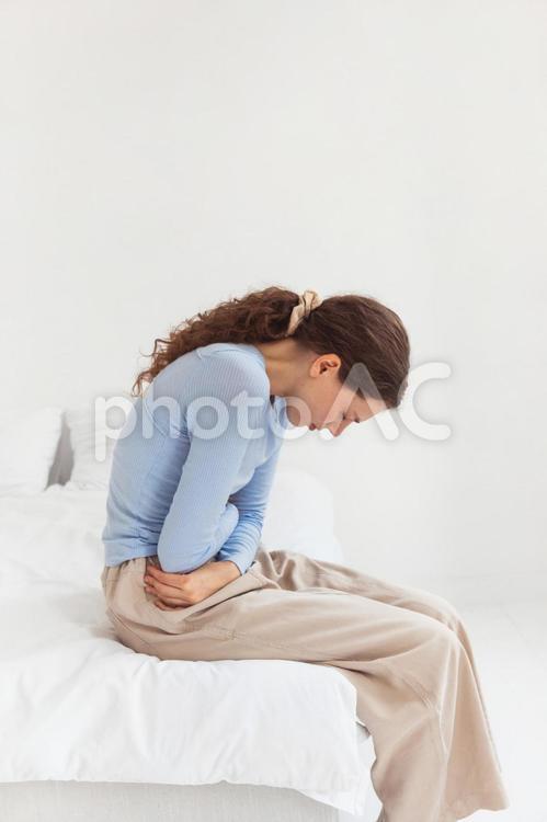 お腹を抑えてうずくまっている女性の横顔 女性,人物,妊娠の写真素材