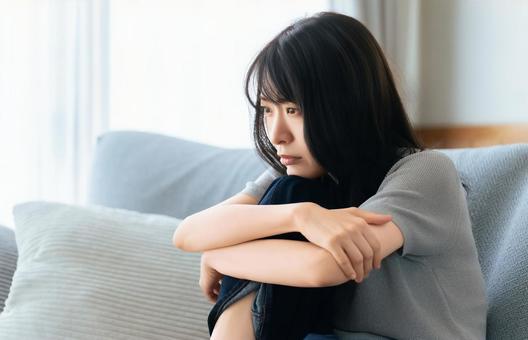 リビングのソファに座って考える女性 リビングのソファに座って考える女性 女性,考える,困るの写真素材