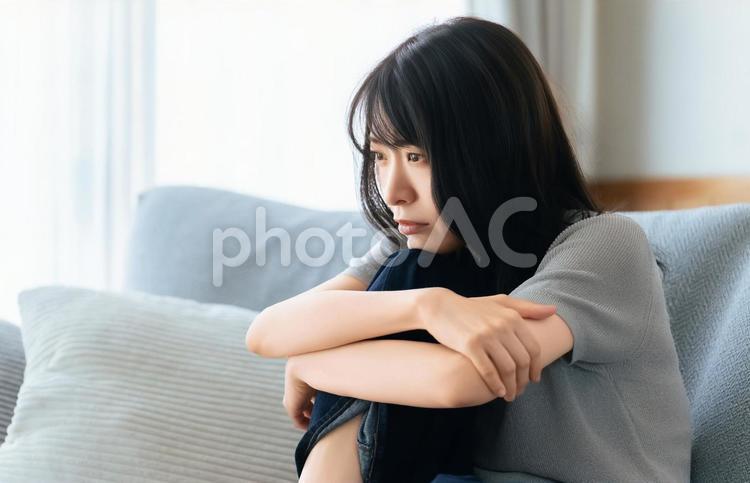 リビングのソファに座って考える女性 女性,考える,困るの写真素材