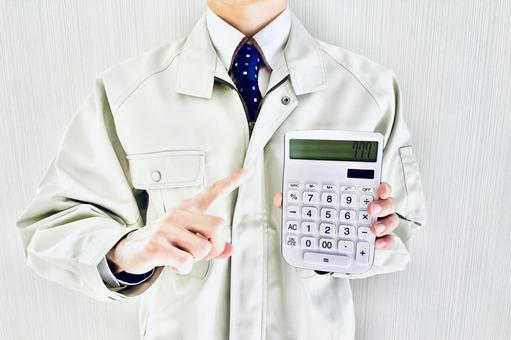 電卓を指差す作業着姿の男性ビジネスマン 作業,コスト,見積もりの写真素材