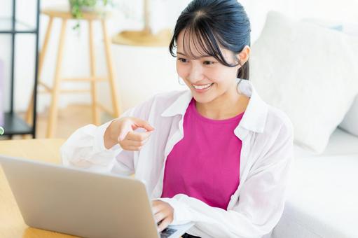 自宅でノートパソコンを操作する若い女性 若い女性,ノートパソコン,笑顔の写真素材