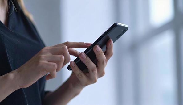 スマートフォンを操作する女性の手元 スマートフォンを操作する女性の手元の写真