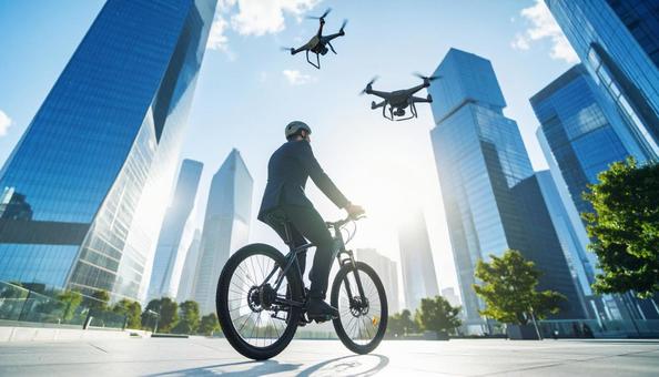 自転車に乗るサラリーマンとドローンの写真