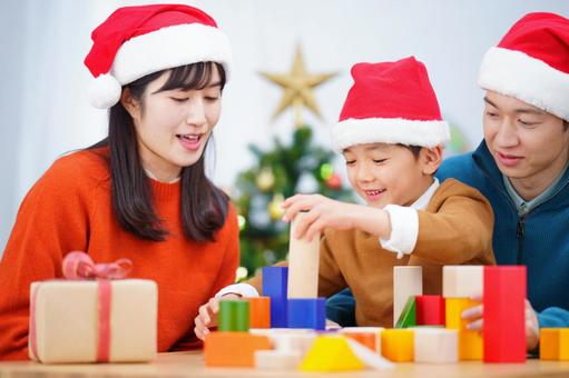 積み木を重ねて遊ぶ男の子と見つめる家族 積み木を重ねて遊ぶ男の子と見つめる家族の写真