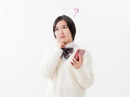 Image of high school girls thinking about holding a smartphone Image of high school girls thinking about holding a smartphone