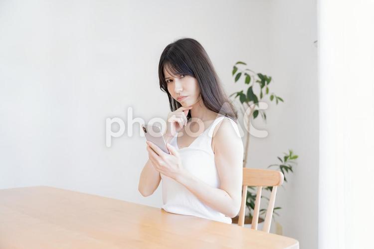 携帯を持ち悩む日本人女性 考える,女性,携帯の写真素材