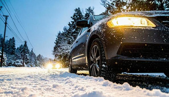 大雪が降った翌日の雪が積もった道を走る車 大雪が降った翌日の雪が積もった道を走る車の写真
