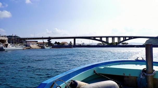 船の上から見た阿嘉島の漁港と阿嘉大橋 船の上から見た阿嘉島の漁港と阿嘉大橋の写真
