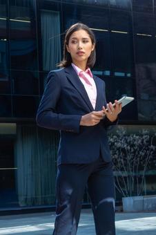 オフィスビルの外でタブレットを持って立っているアジア人ビジネスウーマン ビジネスウーマン,ビジネス,女性の写真素材