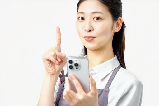 スマホを持ち指さしポーズする主婦 スマホを持ち指さしポーズする主婦 主婦,スマホ,スマートフォンの写真素材