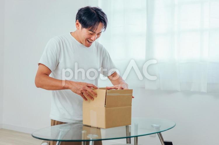 段ボールを開ける男性（喜ぶ） 荷造り,宅急便,宅配便の写真素材