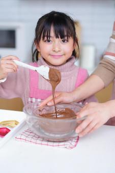 チョコをすくって丁寧に入れる子どもの手元 女の子,チョコレート,ヘラの写真素材