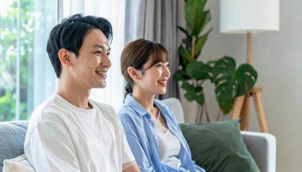 リビングでくつろぐ若いカップルの横顔の写真