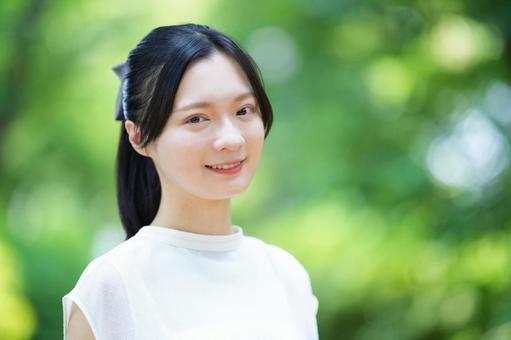 白いノースリーブワンピースの女性が微笑むの写真