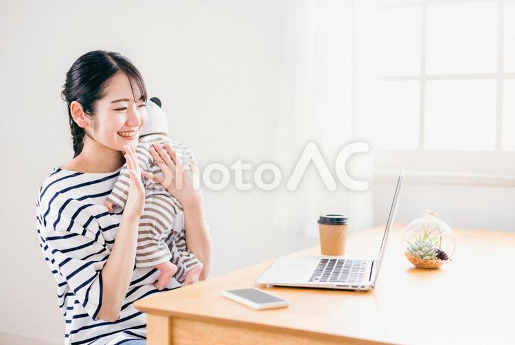 赤ちゃんを抱きながらテレワークする女性 テレワーク,パソコン,赤ちゃんの写真素材