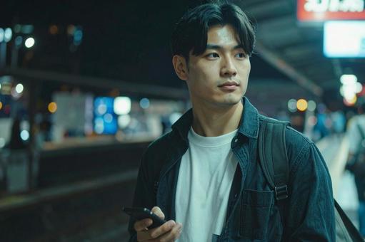 駅のホームで電車を待つ男性 駅のホームで電車を待つ男性の写真