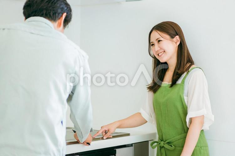 キッチンで話す作業着姿の男性と笑顔の女性 ih調理器,ih,ihクッキングヒーターの写真素材