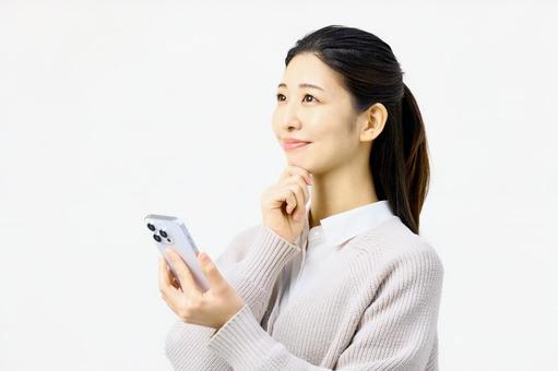 スマホを持ち上を向く女性 スマホを持ち上を向く女性 スマホ,メール,女性の写真素材