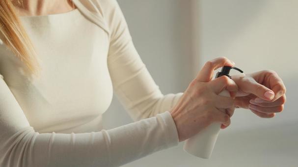 ポンプボトルを押して中身を出す女性の上半身 ポンプボトルを押して中身を出す女性の上半身の写真