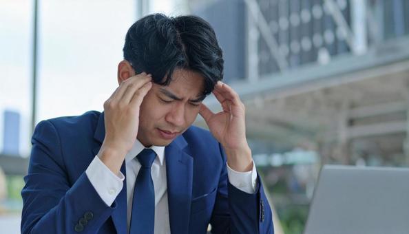 頭を押さえて悩む男性ビジネスマン 頭を押さえて悩む男性ビジネスマンの写真