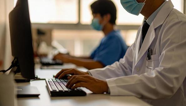 病院で電子カルテに入力する男性の手もとの写真