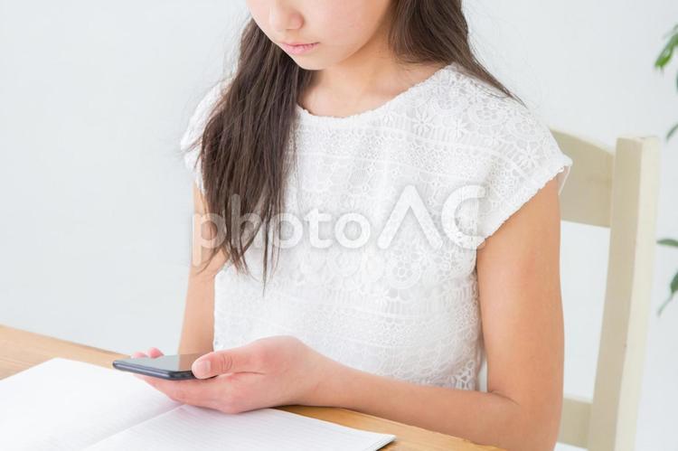 スマホを見ながら勉強する女の子 スマホ,つまらない,アプリの写真素材