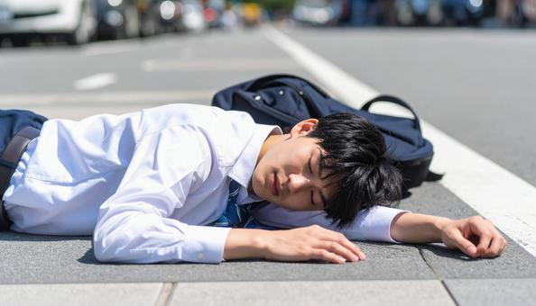 暑さでダウンし、路上に倒れる男子生徒の写真