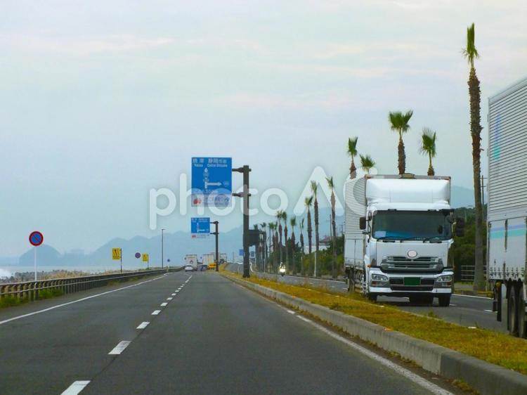 トラックが続く国道と打ち寄せる高波の風景 トラック,列,トラックドライバーの写真素材