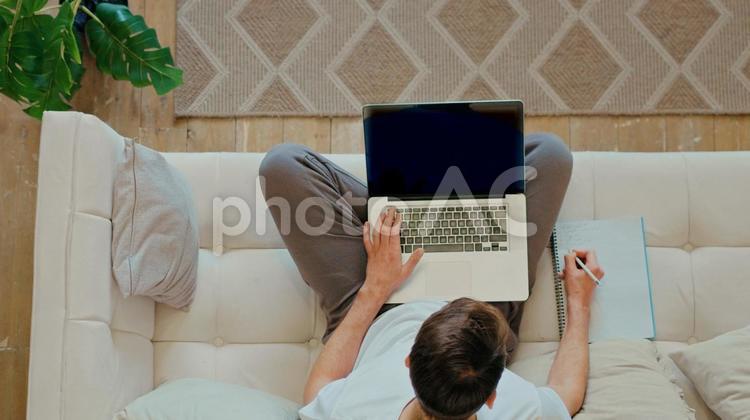 ソファーでパソコンで仕事をする男性 男性,パソコン,ノートパソコンの写真素材