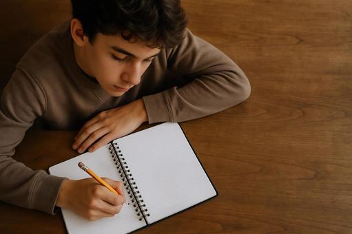 ノートに集中して書き込む男の子 ノートに集中して書き込む男の子の写真